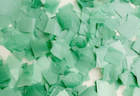 Abstract composition of overlapping green paper squares creating a vibrant textured pattern.