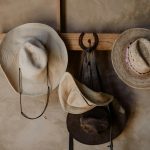 A variety of traditional Mexican hats hang on a rustic wooden rack indoors.