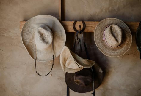 A variety of traditional Mexican hats hang on a rustic wooden rack indoors.
