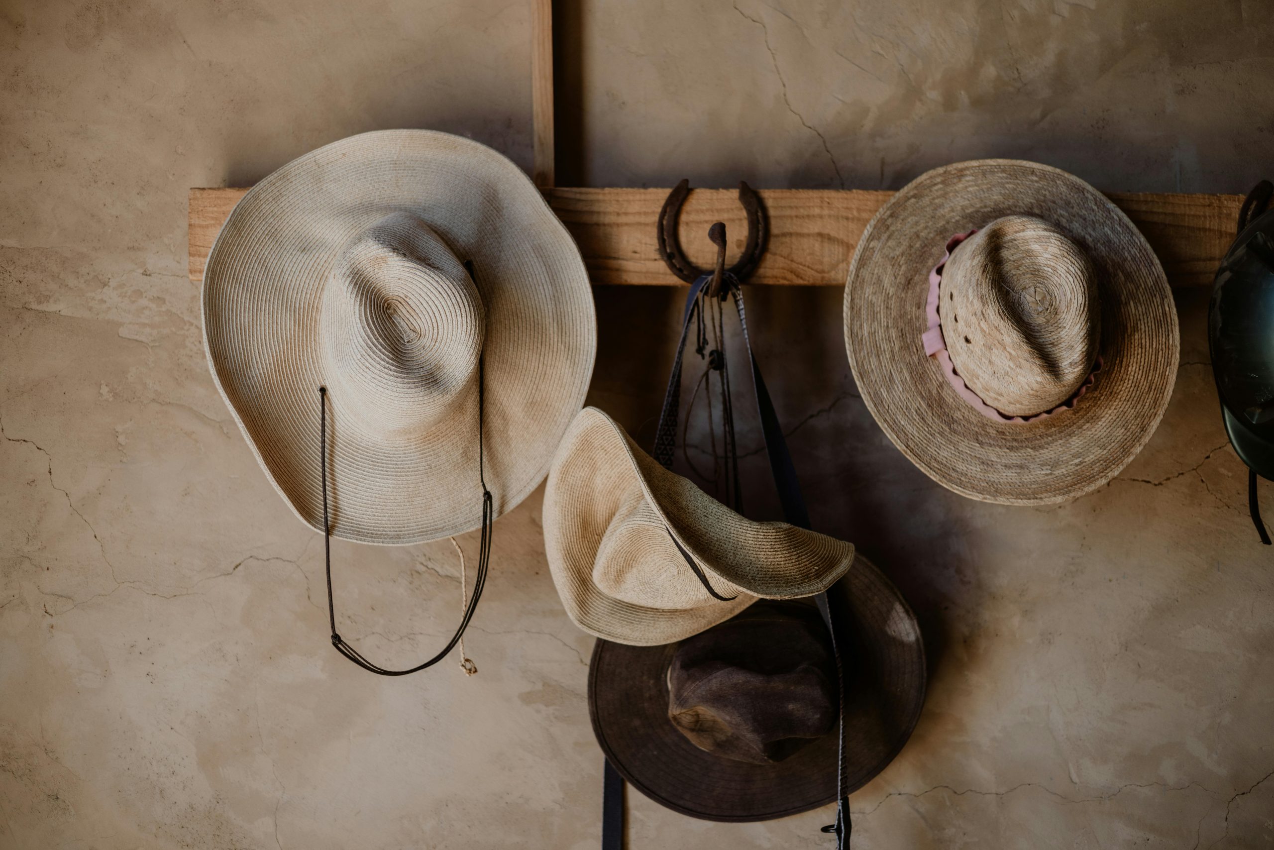 A variety of traditional Mexican hats hang on a rustic wooden rack indoors.
